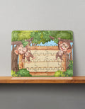 Rectangular MDF wooden puzzle with cartoon monkeys on trees and blank wooden sign in forest, front view on shelf